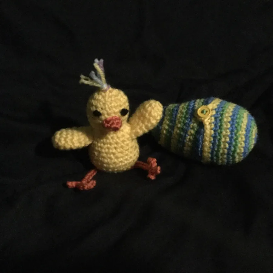 Photo d'origine : un poussin amigurumi et un œuf au crochet sur un tissu noir